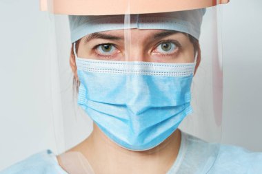 Doktor tıbbi kostüm, maske ve güneşlik takıyor. Koronavirüs salgını sırasındaki kahramanlık tıbbi personeli kavramı.