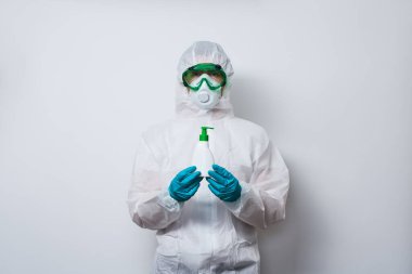 Doktor PPE giyiyor - kostüm, eldivenler ve cerrahi yüz maskesi içinde süper kahraman pelerini ve bir şişe antiseptik sıvı sabun..