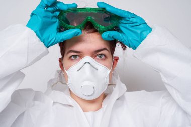 Doktor PPE giyiyor. Kostüm, eldiven ve cerrahi maske..