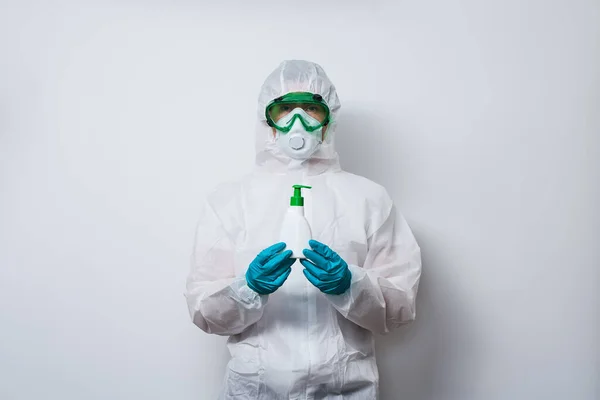 Le médecin porte un EPI costume, gants et masque chirurgical en cape de super-héros avec une bouteille de savon liquide antiseptique . — Photo