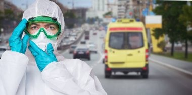 Doktor PPE giyiyor - kostüm, eldivenler ve cerrahi yüz maskesi şehrin arka planında.