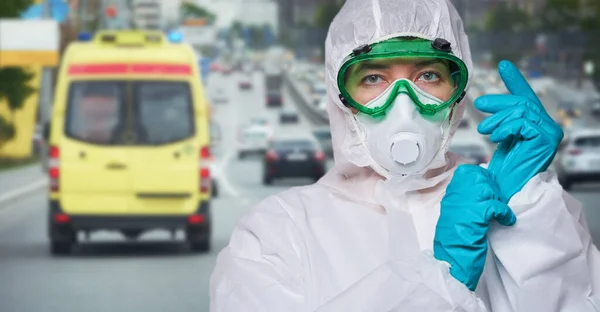 El médico está usando PPE - traje, guantes y mascarilla quirúrgica contra el fondo de la ciudad . —  Fotos de Stock