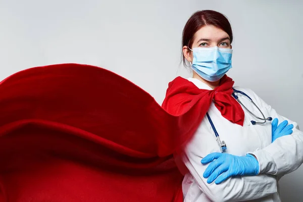 Süper kahraman peleriniyle cerrahi maske takan bir doktor..