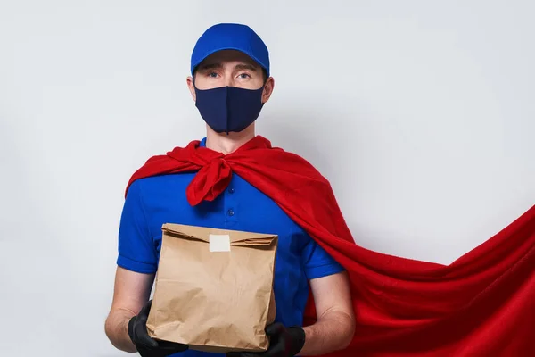 Courier avec sac porte un masque médical dans un manteau de super-héros . — Photo