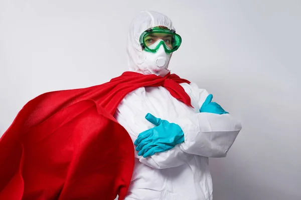 Doktor PPE giyiyor - kostüm, eldivenler ve süper kahraman pelerinli cerrahi maske.