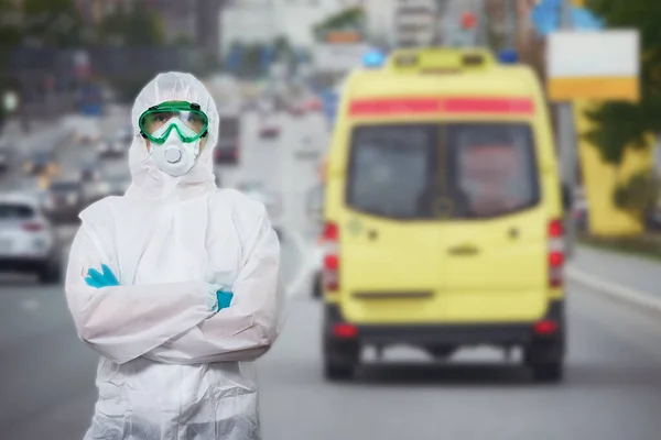 El médico está usando PPE - traje, guantes y mascarilla quirúrgica contra el fondo de la ciudad . —  Fotos de Stock