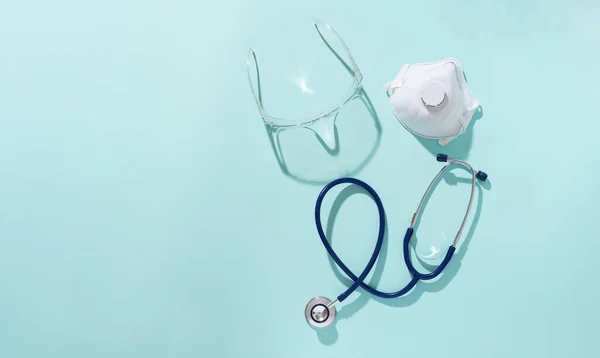 Fonendoskop, respirator och skyddsglasögon på en blå bakgrund. — Stockfoto