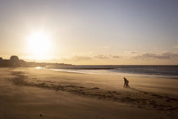 Gün batımında Margate sahilinde yürüyen çift.