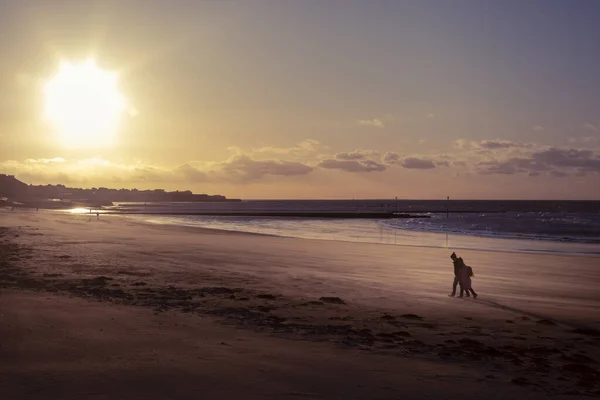 Gün batımında Margate sahilinde yürüyen çift.