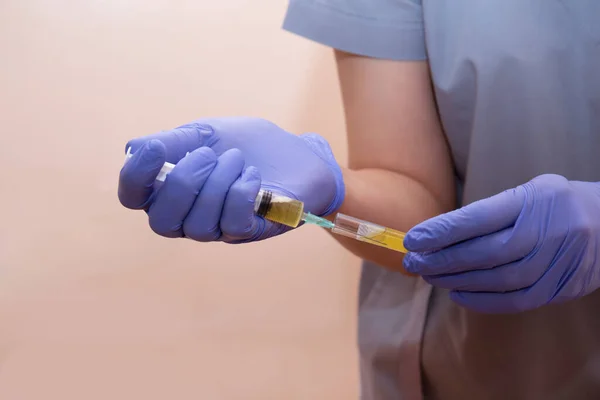 Hands of a nurse collect blood plasma with a syringe from a test tube for prp-therapy.
