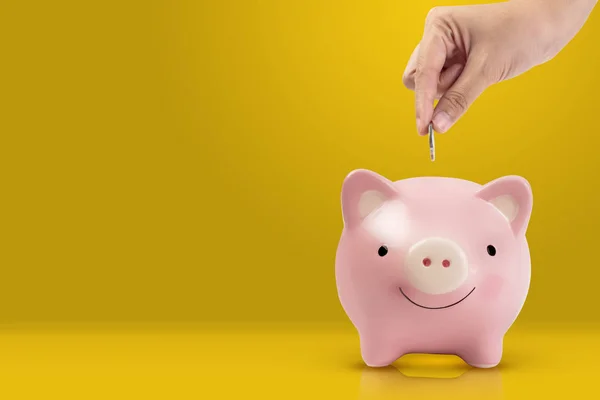 Mulheres Mão Colocando Moeda Rosa Porquinho Banco Fundo Amarelo — Fotografia de Stock