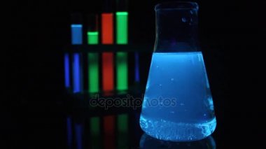 Tıbbi test tüpleri ve şişesi içinde parlayan sıvı kimyasallar.