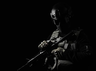 Siyah ve beyaz fotoğraf donanımlı swat asker tüfeği siyah arka plan üzerinde ayakta.