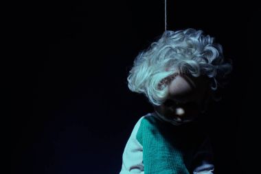 Koyu temalı asılan korkunç mavi siyah arka plan üzerine intihara meyilli bez bebek tonda.