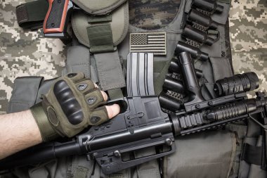 Elinde bir tüfek askeri tactacal kurşun geçirmez yelek, kamuflaj kumaş arka plan üzerinde döşeme Cartridge kemer üzerinde tutarak taktik eldiven üst görünüm fotoğrafı.