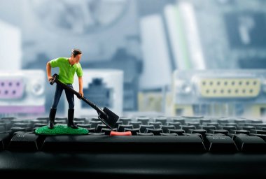 Fotoğraf minyatür oyuncak işçisi kürek bilgisayar klavye tuşları üzerinde çalışma ile.