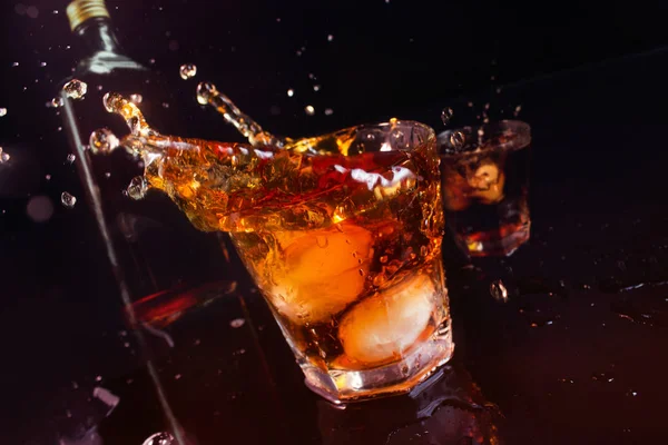 Whiskey bottle with glasses spilling with ice. — Stock Photo, Image