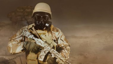 Üniformalı ve gaz maskeli asker elinde tüfekle çölde duruyor..