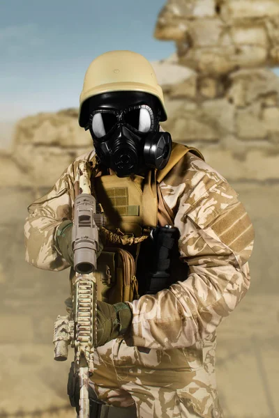 Soldado de uniforme e máscara de gás atacando com rifle no deserto . — Fotografia de Stock