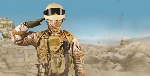Soldado en uniforme de pie en el desierto saludando . — Foto de Stock