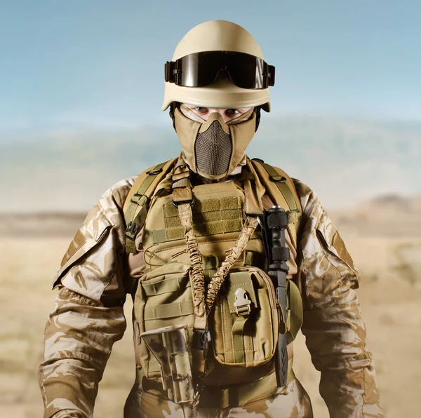 Soldier in uniform standing in desert.