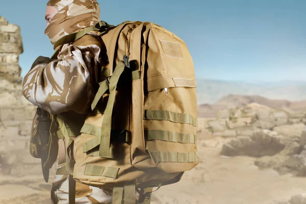 Soldat i uniform stående med ryggsäck på öknen bakgrund. — Stockfoto