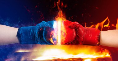 Erkek ellerinin kırmızı ve mavi boks eldivenleriyle ateş ve patlama efektlerinin yanan arka planda fotoğrafı..