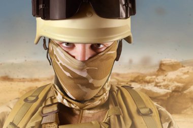 Tam teçhizatlı bir çöl askerinin tozlu çöl arka planında çekilmiş fotoğrafı..