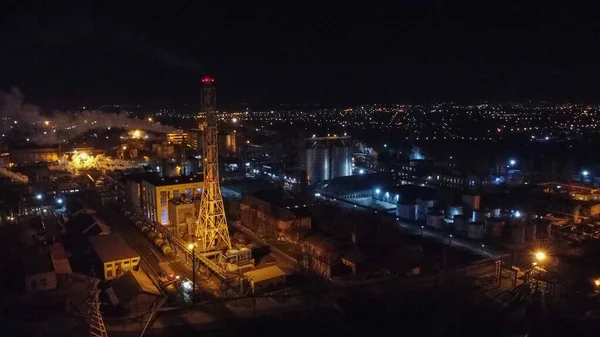 Aerial view of oil factory with gas tank , night city on background.