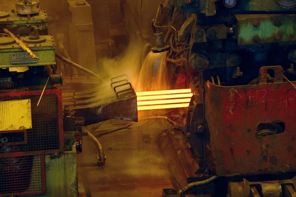 Rolling hot steel to wire in four strand rolling mill.