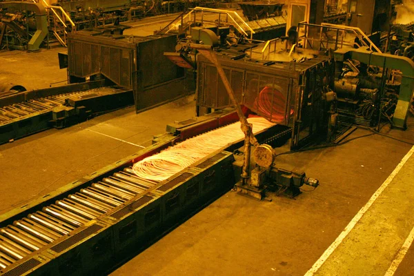 Rolling hot steel to wire in four strand rolling mill. Coiling cooling bank.