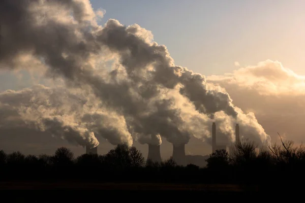 large cloud of steam from coal fire power station cooling towers in evening light.