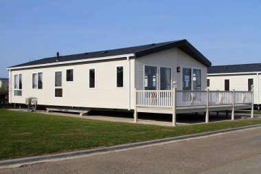 Önünde balkon olan deniz kenarındaki parkta büyük bir karavan. Kiralık ya da satın alınabilir. Uk.