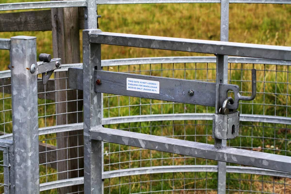 Galvanized steel fam gate with padlock to keep livestock in and trespassers out.