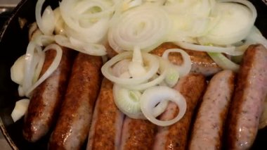 Domuz sosisi ve soğan kızartma tavasında pişiriliyor. Mutfakta, ocağın üstünde..