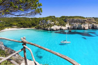 Beautiful beach with sailing boat yacht, Menorca island, Spain. Yachting, travel and active lifestyle concept clipart