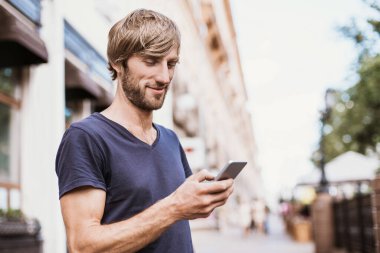 Genç adam akıllı telefon kullanıyor. 