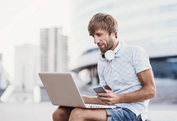 Jovem Com Smartphone Usando Laptop — Fotografia de Stock