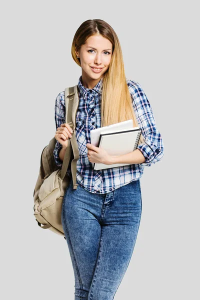 Sırt çantalı güzel bir kadın kitap tutuyor. 