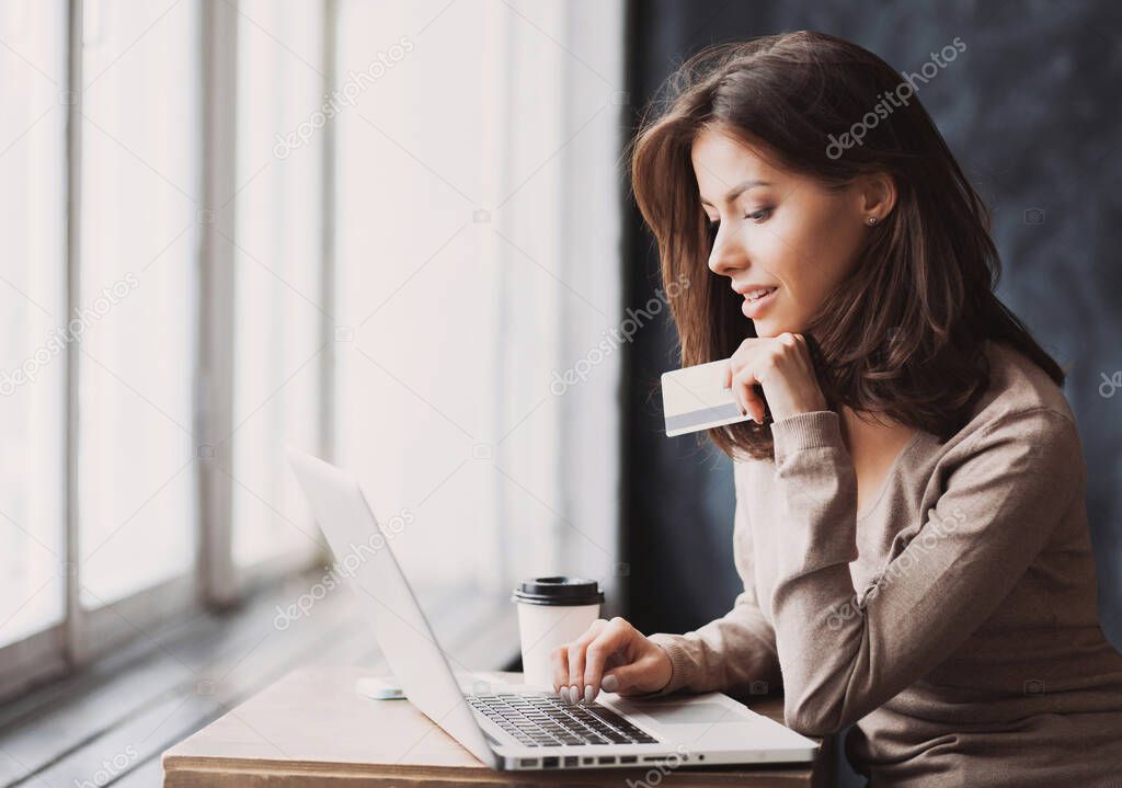 Young woman holding credit card and using laptop computer, beautiful businesswoman shopping online