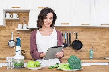 Yemek pişirirken tablet kullanan güzel bir kadın. 