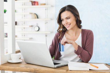 Bilgisayar kullanan ve internetten alışveriş yapan güzel bir kadın.