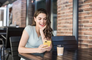 Kafede akıllı telefon kullanan güzel bir kadın. 