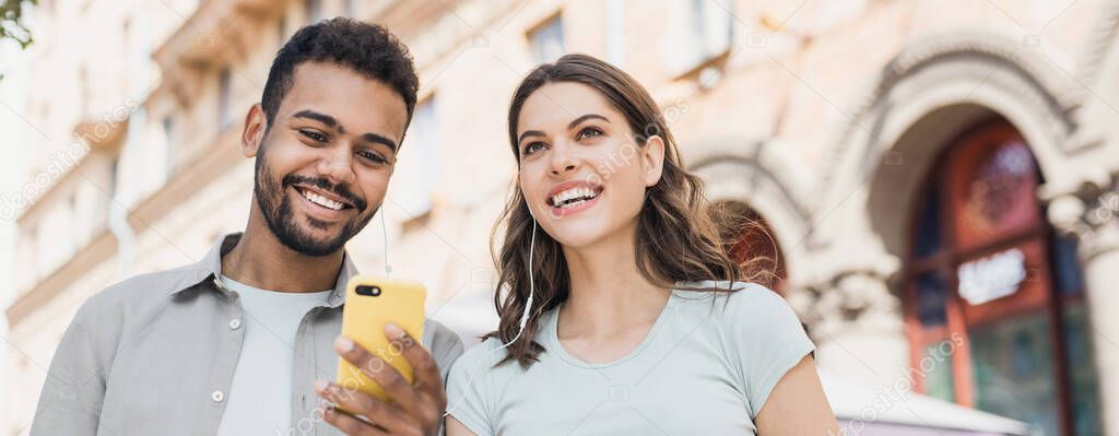 Beautiful happy young couple using smartphone together outdoors panoramic banner, joyful smiling woman and man looking at mobile phone in city, Love, technology, communication, summer travel concept