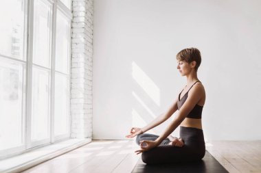 Genç bir kadın meditasyon yapıyor. Sınıfta yoga yapan bir kız. Rahatlama, vücut bakımı, meditasyon, denge, uyum, dinlenme konsepti