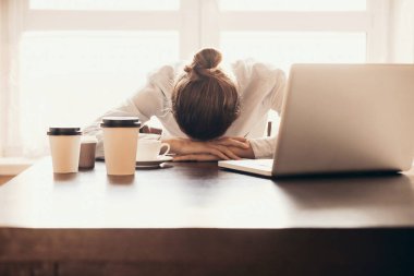 Ofiste masada uyuyan yorgun iş kadını. Evden çalışan çok yorgun genç bir kız. Laptop kullanan bir kadın. Girişimci, iş adamı, serbest meslek, öğrenci, stres, ev kavramından çalışma