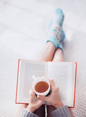 Kız çay içerken kitap okuyor.