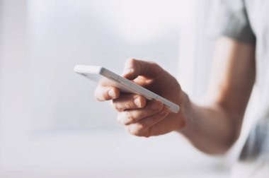 Kadın elleri dışarıda akıllı bir telefon tutuyor.