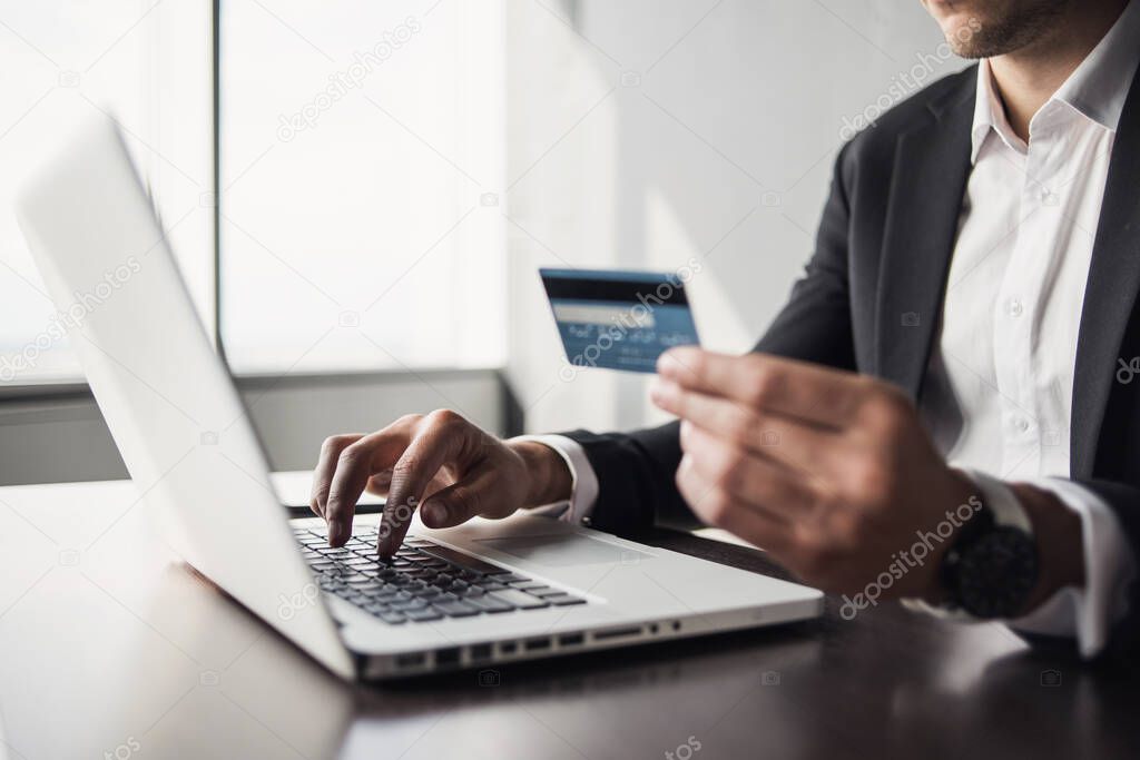 Hand holding credit card and using laptop. Businesswoman or entrepreneur working from home. Online shopping, e-commerce, internet banking, spending money, work from home concept 