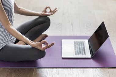 Evde yoga yapan genç bir kadın. Çevrimiçi video eğitimi. Egzersiz ve meditasyon yapan bir kız. Yoga, denge, meditasyon, rahatlama, sağlıklı yaşam tarzı, online eğitim sınıfı konsepti.